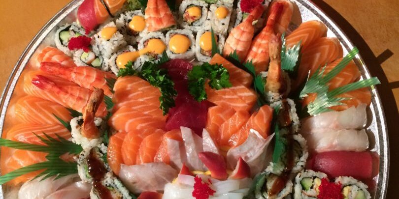 A party tray containing a combination of sushi, rolls, and sashimi